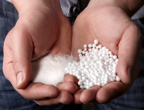 Links der Rohstoff Polystyrol, rechts die geschäumten EPS-Kügelchen: Der Rohstoff für geschäumte Polystyrol-Kügelchen (EPS) besteht aus kleinen, festen Polystyrol-Partikeln, die ein Treibmittel wie Pentan enthalten. Durch Einwirkung von heißem Wasserdampf dehnt sich das Pentan aus, wodurch sich die Kügelchen zu leichten, schaumigen Perlen aufblähen und somit expandiertes Polystyrol (EPS) bilden.